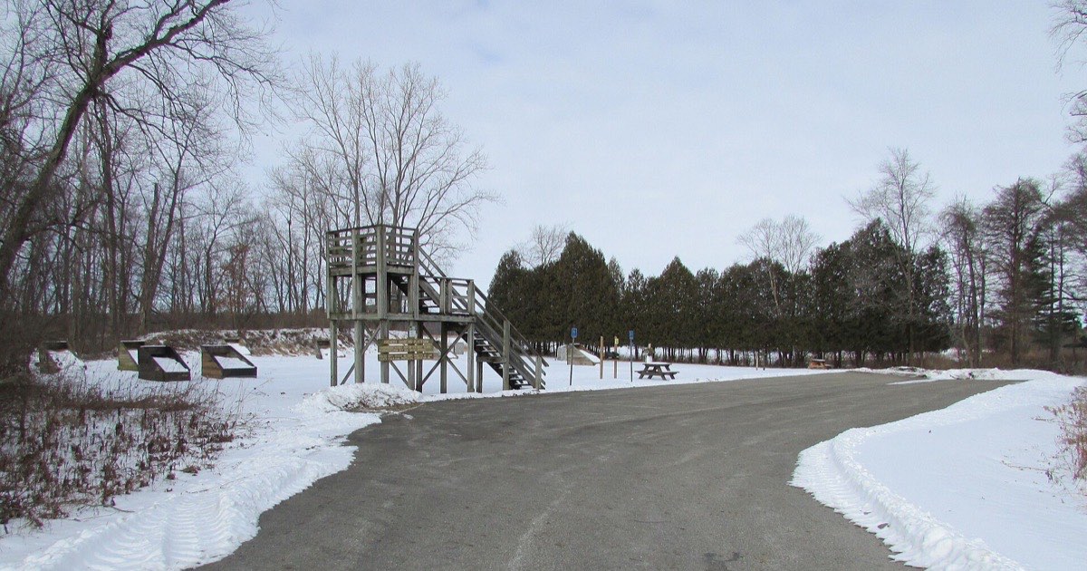 Outdoor archery range in winter with target butts and a shooting tower beside snow-covered ground