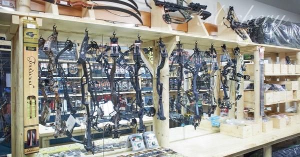 Archery shop wall lined with compound and recurve bows, arrows and accessories