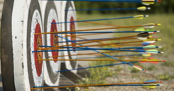 Many arrows with coloured fletchings grouped in the centre of a target face