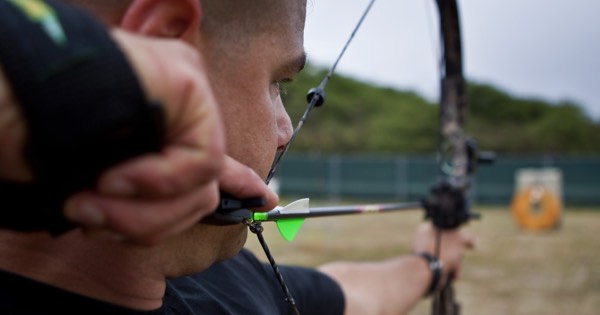Close-up of a compound archer at anchor with a wrist-strap release aid and peep sight
