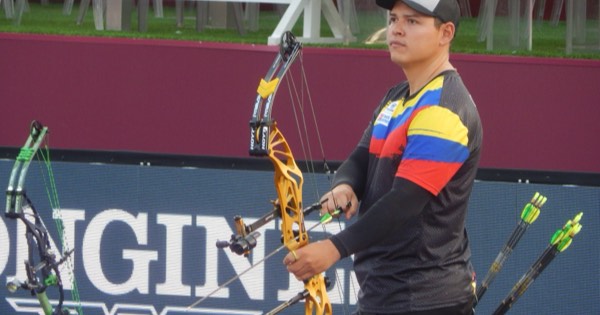A compound archer holding a target bow fitted with a long front stabiliser