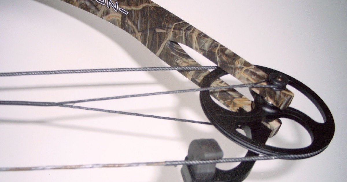 Round idler wheel and stop at the limb tip of a camouflage compound bow, with the string and cables