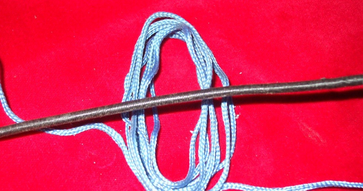 Light blue D-loop cord looped around a dark bowstring before being tied and tightened