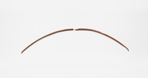 Two curved sections of an ancient Egyptian composite bow made of birch wood and horn, on a white background