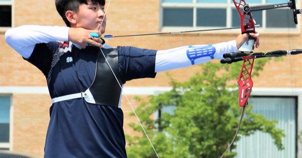 Kim Je-deok of South Korea at full draw with a red recurve riser during outdoor practice
