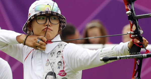 Olympic recurve archer at full draw with a red competition riser and sight at London 2012