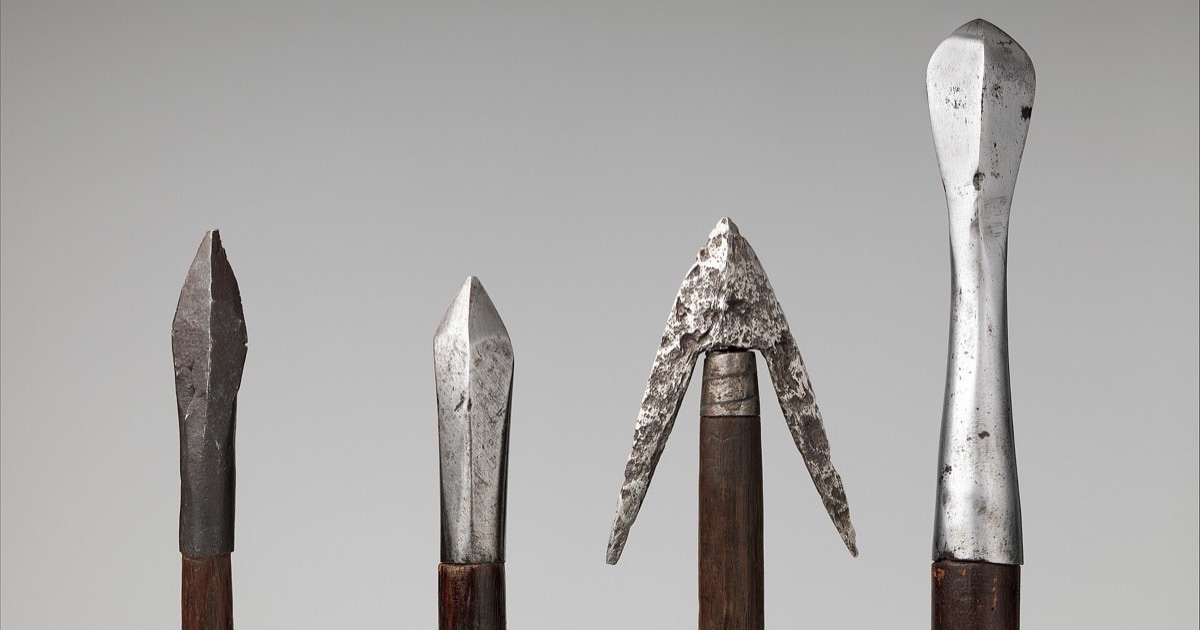 Close-up of four European crossbow bolt heads in the Metropolitan Museum of Art, including faceted, barbed and long chisel-like heads on wooden shafts