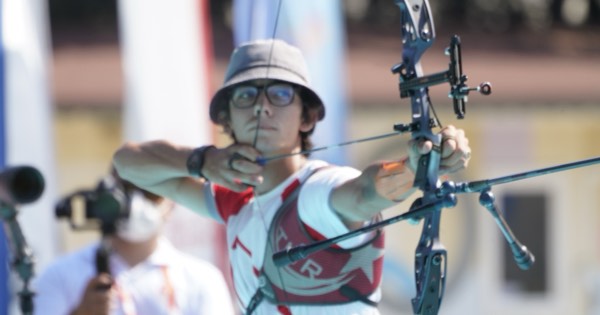 Mete Gazoz of Türkiye at full draw with a recurve bow at an outdoor competition