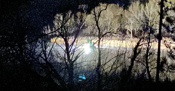 Bowfishers working from a lit boat on a river at night