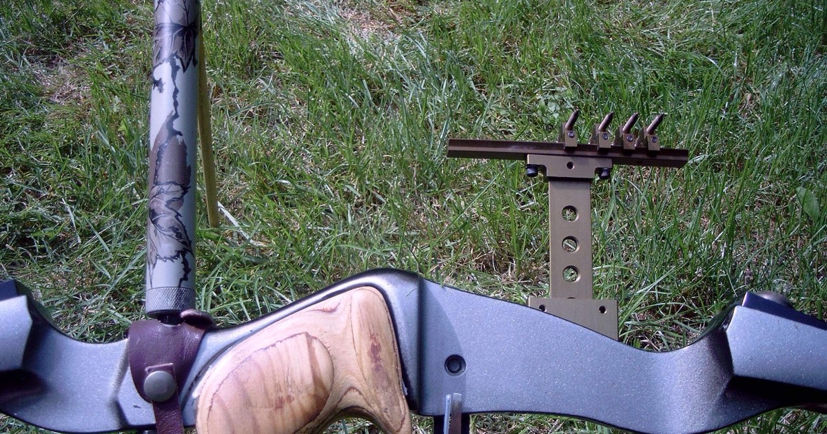 Close-up of a hunting recurve riser showing the arrow shelf, grip and a multi-pin sight